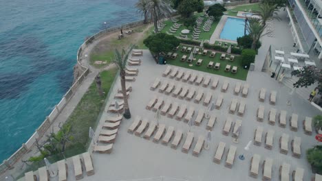revealing drone clip over a luxurius swimming pool, a hotel resort and the mediterranean sea in mallorca, spain