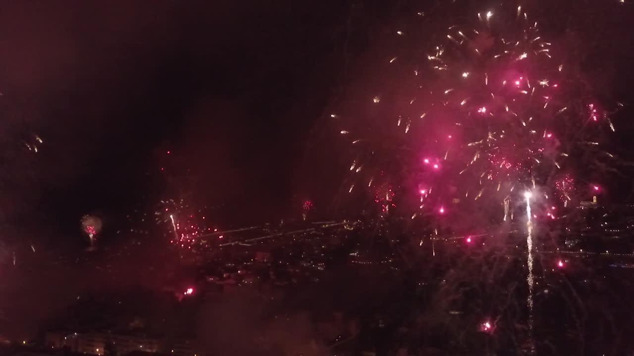 toma panorámica lenta de coloridas explosiones de fuegos artificiales rojos y verdes en lo alto de la ciudad en la isla de madeira