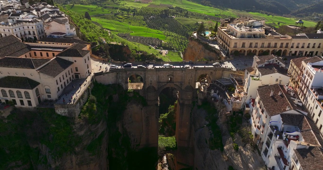 Imágenes de dron sobre la ciudad de Ronda, ubicada en España, Europa. Ángulo de cámara cenital, inclinándose hacia arriba. Tejados, puente y rocas son visibles en el encuadre. Metraje 4K ProRes de alta calidad