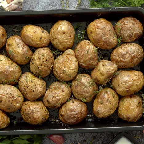 tasty fresh homemade baked potatoes served on a metal tray  with various herbs  butter  garlic  salt