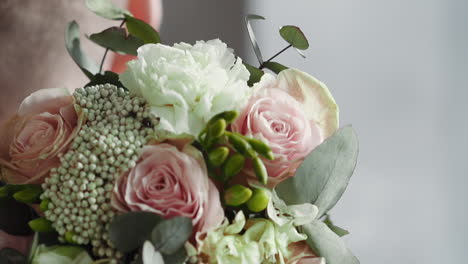 groom puts elegant wedding bouquet on shoulder in studio