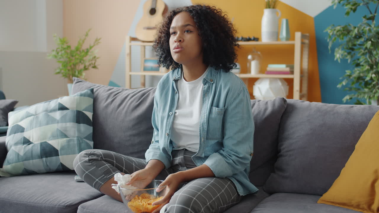 Teenager ser tv og spiser chips