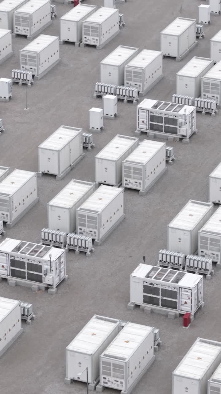 Riprese aeree con drone di unità di batterie per l'accumulo di energia in un impianto di energia rinnovabile, avvolto nella nebbia, che illustrano lo stoccaggio sostenibile di elettricità e la moderna infrastruttura energetica.