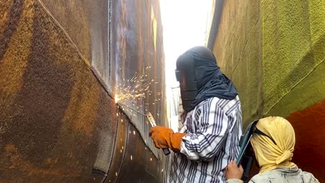 Two-worker-welding-ship-hull-wearing-welding-mask-for-safety