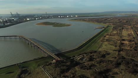 Aerial-:-Descending-drone-shot-above-pier-with-industry-and-tankers-in-distance