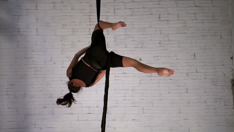 woman acrobat practicing acrobatic stunts in the air while hanging upside down, still shot