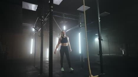 a sporty young woman pulls herself up on a horizontal bar in a dark gym in a beautiful neon backlight. endurance and perseverance in pulling up movement towards the goal