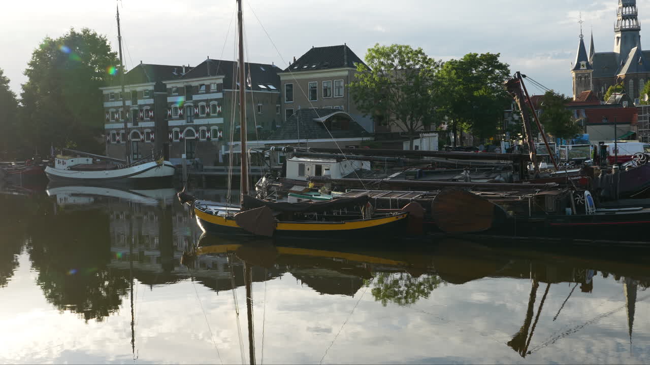 네덜란드 가우다 의 옛 항구 에 있는 전통적 인 배 들 이 운하 물 에 반사 되어 있다
