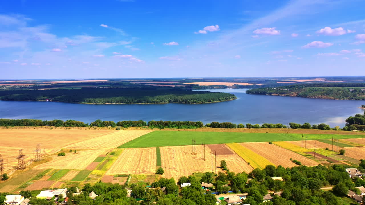 Stunning view of the wheat fields, river and forests on sunny summer day. Beautiful blue skies with rare clouds at backdrop.