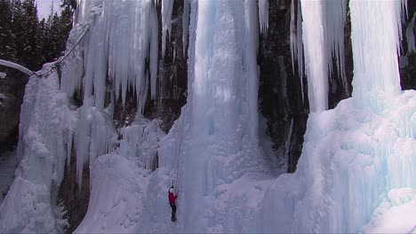 wide shot of a man climbing up a frozen waterfall