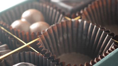 close-up of a hand taking and placing chocolates in a box