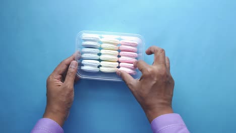 hands holding a box of colorful macarons