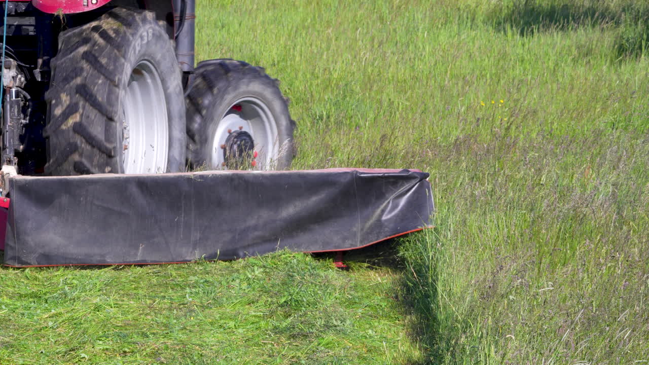 Tractor mowing grass on airfield at, preparing runway surroundings