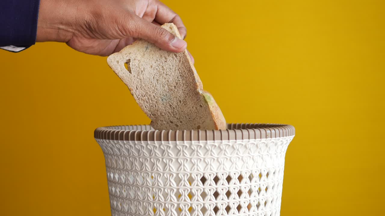 tirando panes en un cubo de basura ,