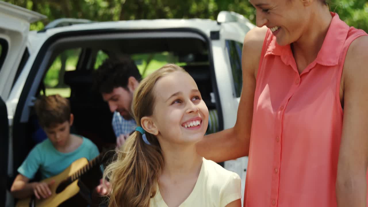 아버지 와 아들 이 기타 를 연주 하는 동안 피크닉 바구니 와 함께 서 있는 어머니 와 딸 의 초상화