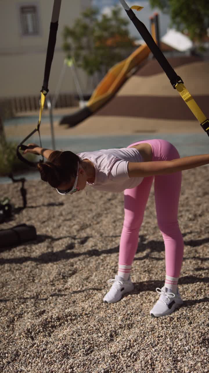 Woman exercising outdoors with suspension training equipment