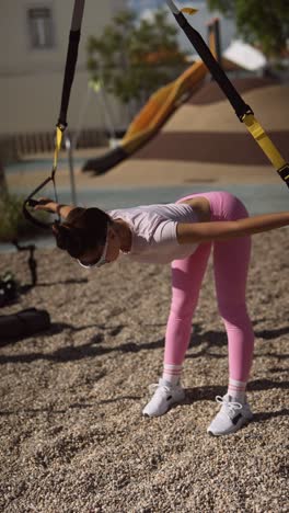 woman exercising outdoors with suspension training equipment