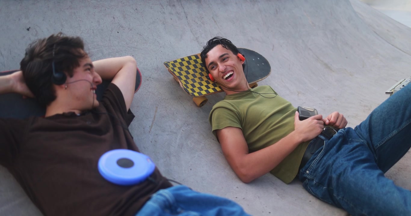 Due ragazzi che si rilassano e ascoltano musica in uno skatepark