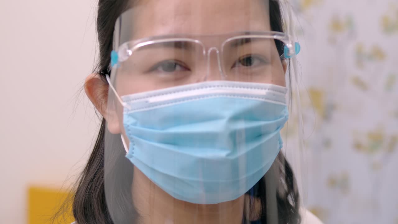 Portrait of an Asia young female who is wearing a face shield with mask rounded around her face from a frontal perspective to protect her glasses and eyes, scene of slow motion