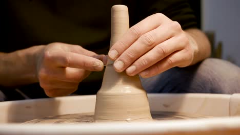 man's hands making clay ware on the potter's wheel