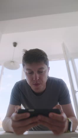 Man using smartphone indoors near a window
