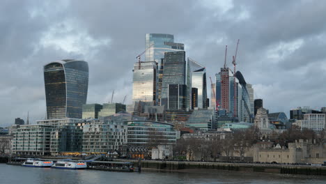 city of london skyscrapers and modern office buildings with tower pier on river thames with overcast