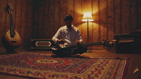 musician playing a traditional indian sitar in a warmly lit room