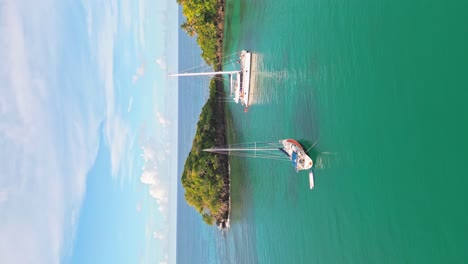 vertical aerial forward flight approaching luxury catamaran in tropical bay during summer - playa bonita,dominican republic