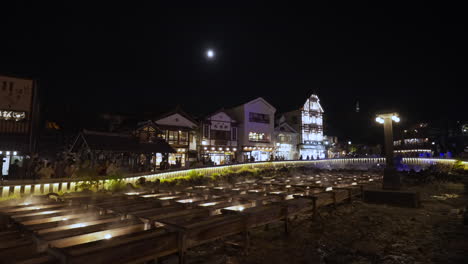 plano general del icónico yubatake de kusatsu onsen en gunma por la noche después de la iluminación, con arquitectura japonesa y turistas en el fondo