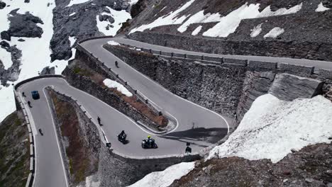 two motorcyclists ride along a scenic mountain road in the alps, as a drone captures spectacular aerial footage