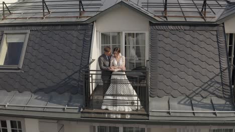 Caucasian-newlyweds-bride-embracing-groom-on-balcony-in-hotel-room,-aerial-view