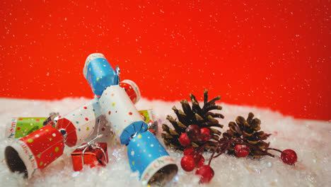 animation of snow falling against christmas crackers decorations on red