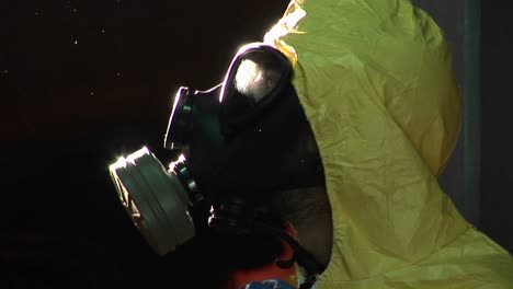 un hombre con un traje de materiales peligrosos y una máscara de gas se convierte en perfil