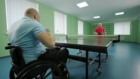 un hombre en silla de ruedas juega ping pong. personas con discapacidad juegan tenis de mesa. rehabilitación de discapacitados. deporte paralímpico.