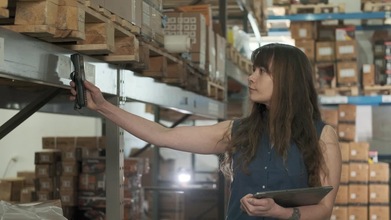 el gerente utiliza el escáner para comprobar las mercancías en los estantes del centro de distribución