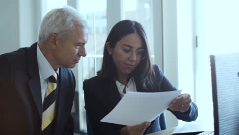 young female manager and grey haired male executive analyzing data