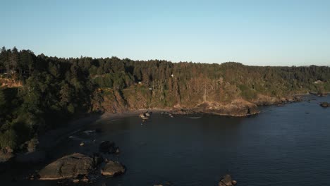 Calm-ocean-water,-nature’s-coastline-of-cliffs,-trees-and-vegetation