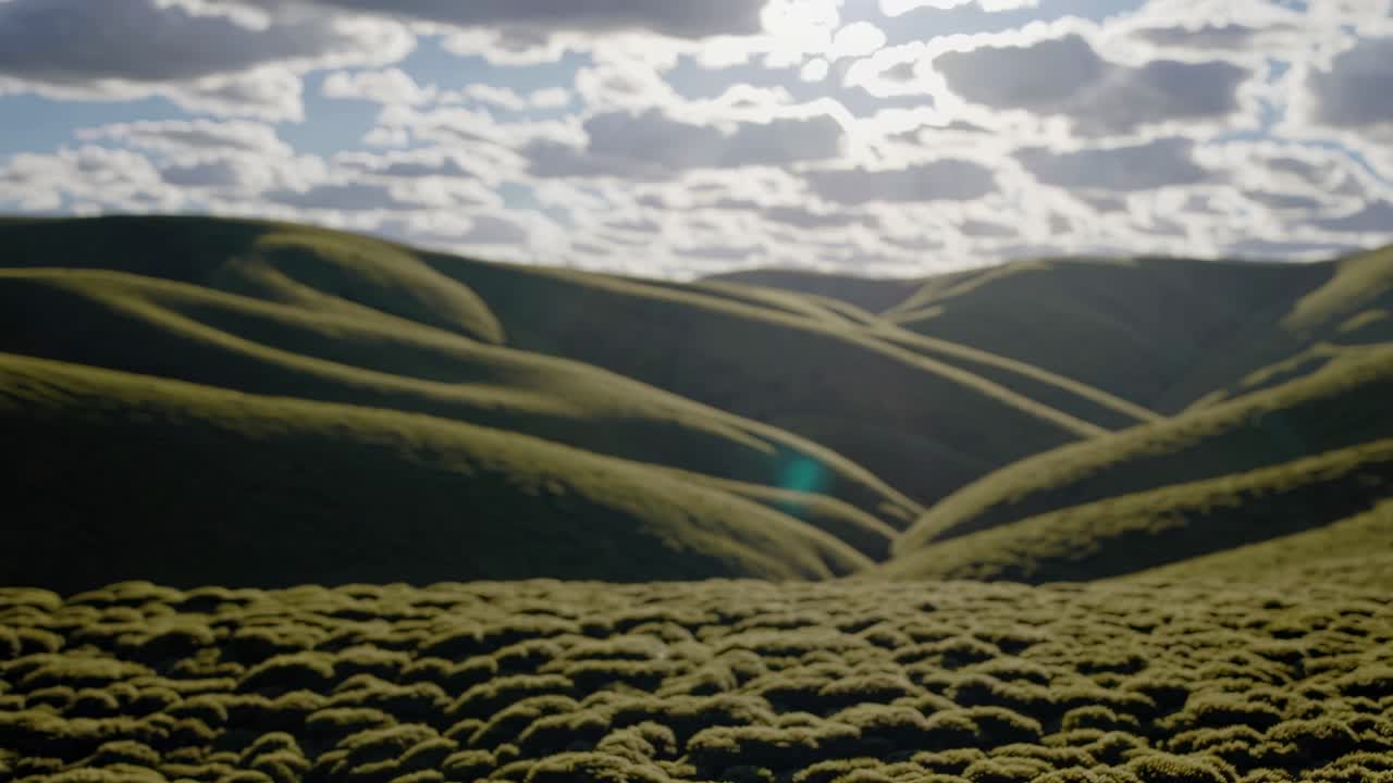Aerial video of rolling green hills under a cloudy sky, capturing a serene landscape