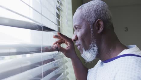 African-american-male-patient-looking-at-window-in-hospital-room-smiling