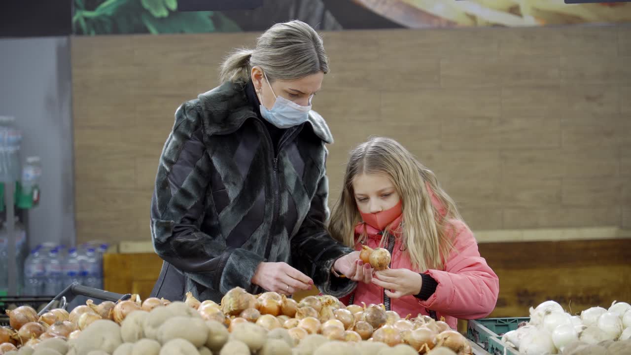 madre e hija eligen los productos en la tienda. mamá muestra cómo hacer la elección correcta de verduras.