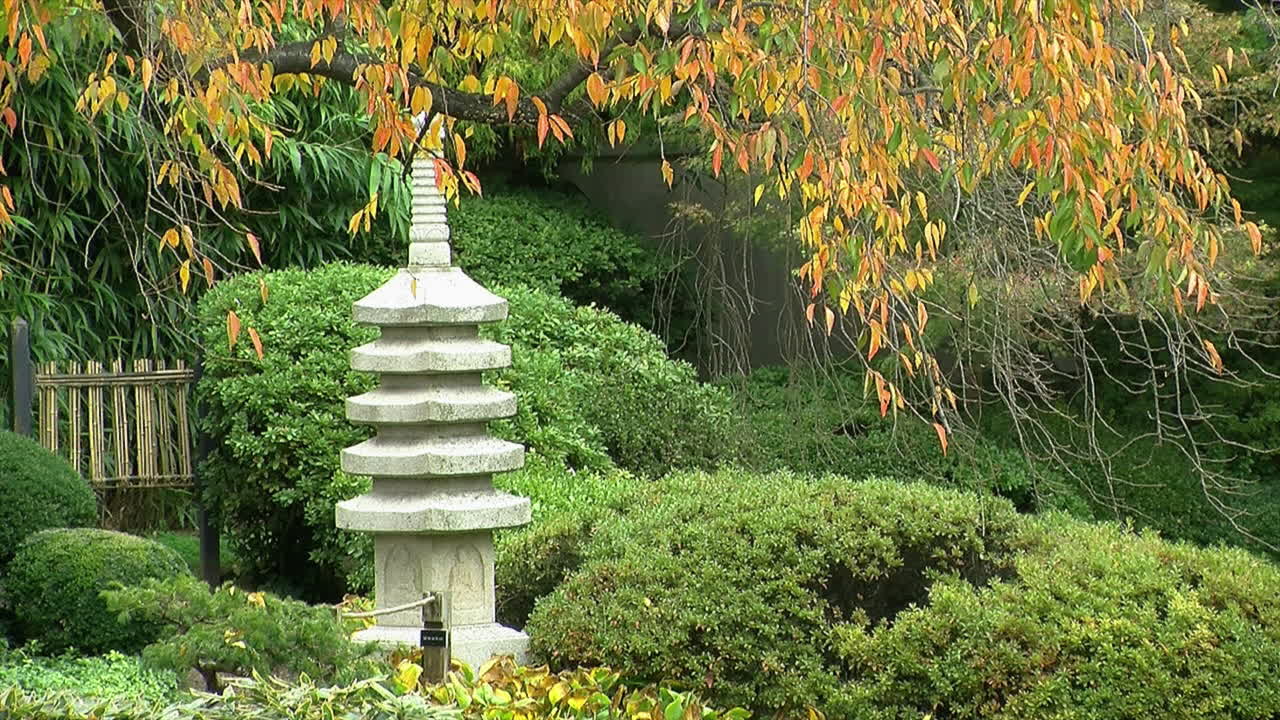 Pagoda in pietra e cancello di bambù in un giardino giapponese in autunno.