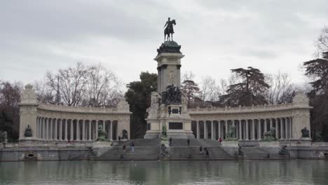 Turistas-En-El-Parque-Del-Buen-Retiro-Con-El-Monumento-Alfonso-Xii-Frente-Al-Lago-En-Madrid,-España