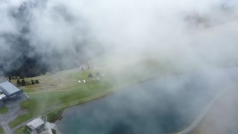 drone pans camera con las nubes flotando sobre un hermoso y pequeño embalse en la montaña asitz kogel en austria, leogang saalbach