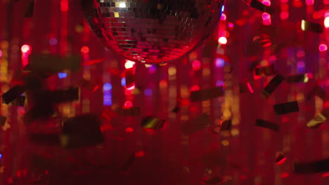 close up of revolving mirrorball in night club or disco with flashing strobe lighting and falling golden confetti