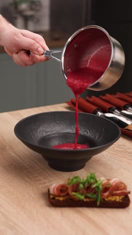 chef pouring beetroot soup into a bowl