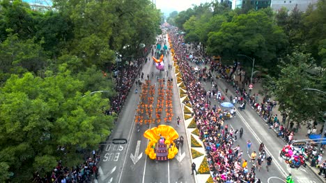 overhead drone shot of the day of the dead parade in mexico city with people in costumes and floats