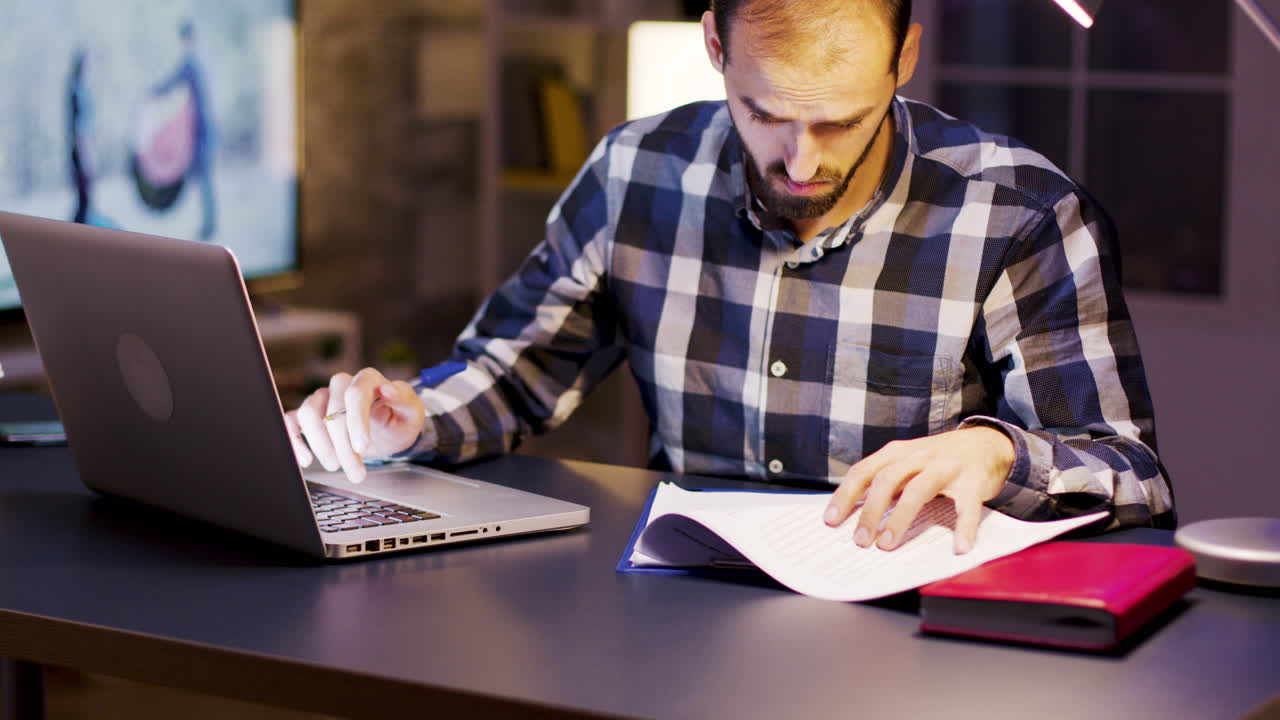 Man working on laptop with documents at desk