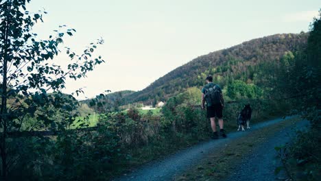 Indre-Fosen,-Noruega---Un-Hombre-Y-Su-Perro-Están-Dando-Un-Tranquilo-Paseo-Por-Una-Ruta-De-Peregrinación-Costera---Toma-Estática