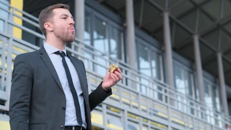 man in suit eating a sandwich outdoors