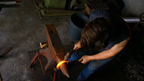 female metalsmith molding horseshoe in factory 4k